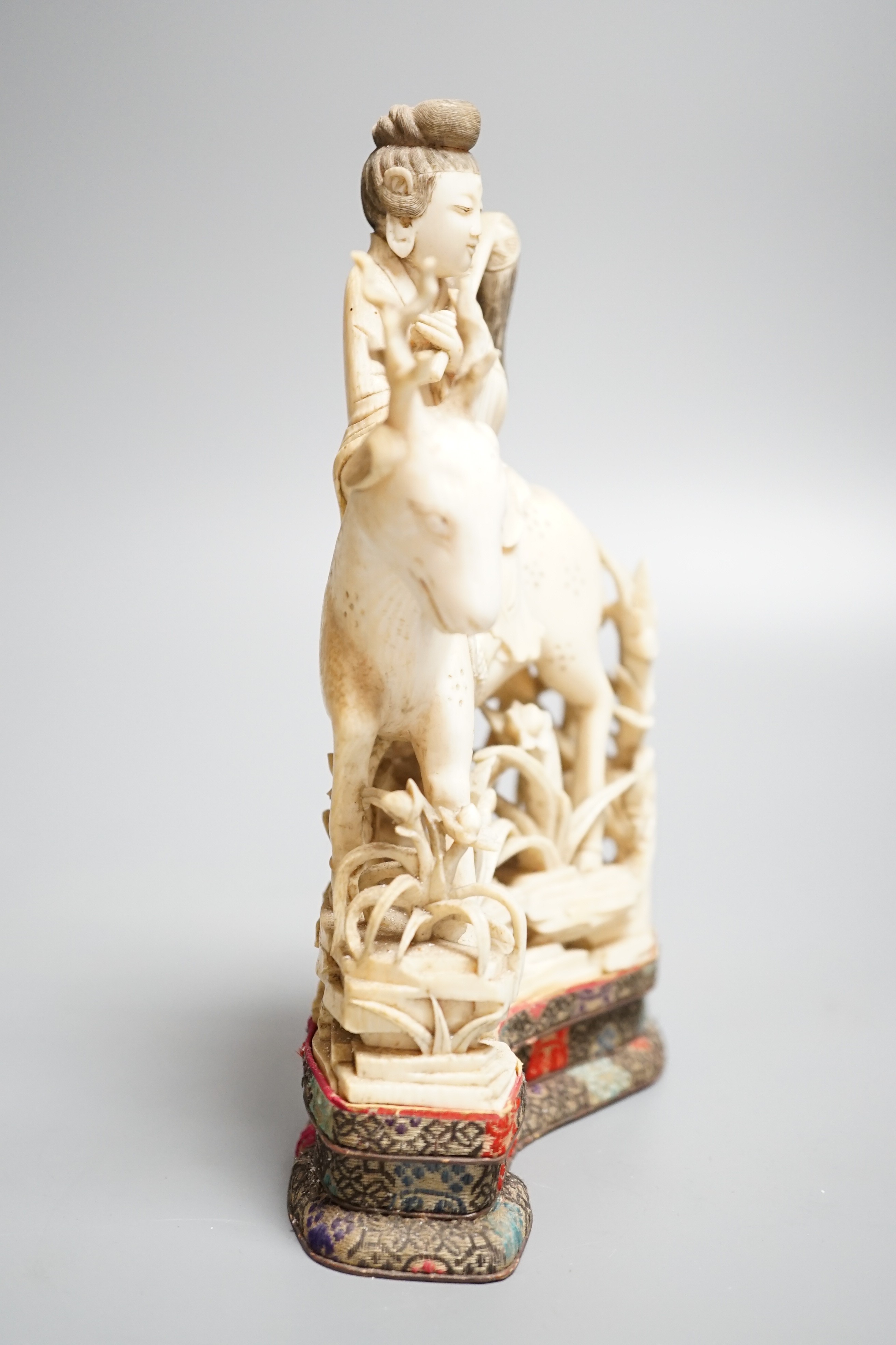 A Chinese carved ivory figure of a female immortal riding a deer, early 20th century, height 17cm excl. stand
